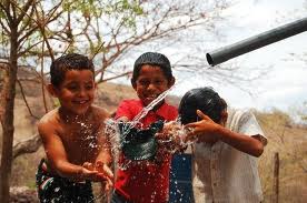 children playing and washing with water from pipe